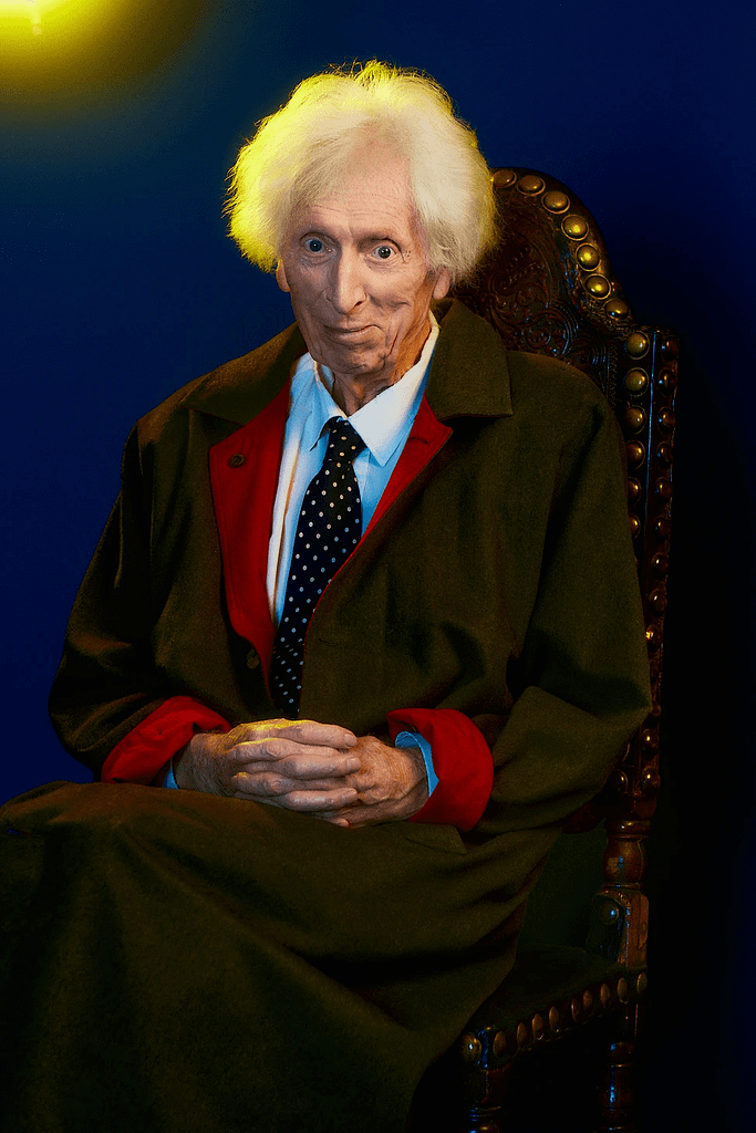 Tom Baker sentado en una silla sonriendo a la cámara