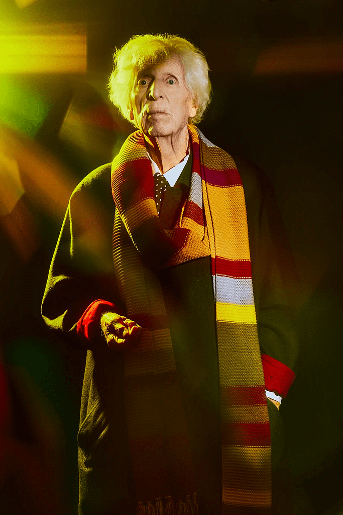 Tom Baker con una réplica de su bufanda del Cuarto Doctor, de pie.