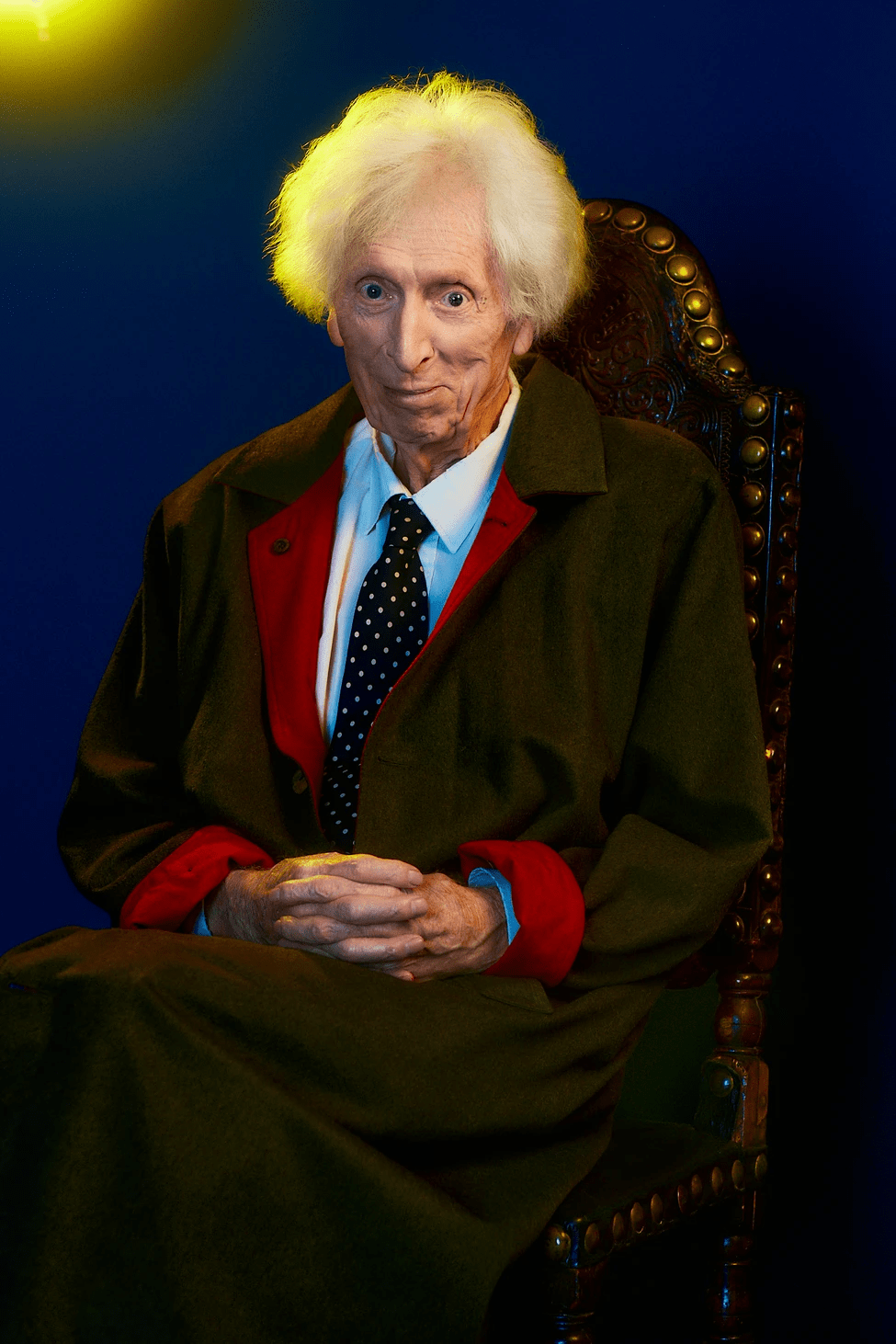 Tom Baker sentado en una silla sonriendo a la cámara